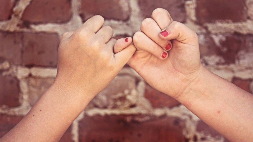 Two women pinky swear