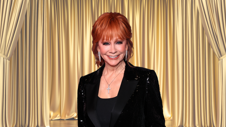 Reba McEntire smiling in front of a gold curtain
