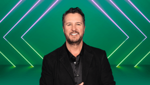 Luke Bryan smiling on a colorful stage