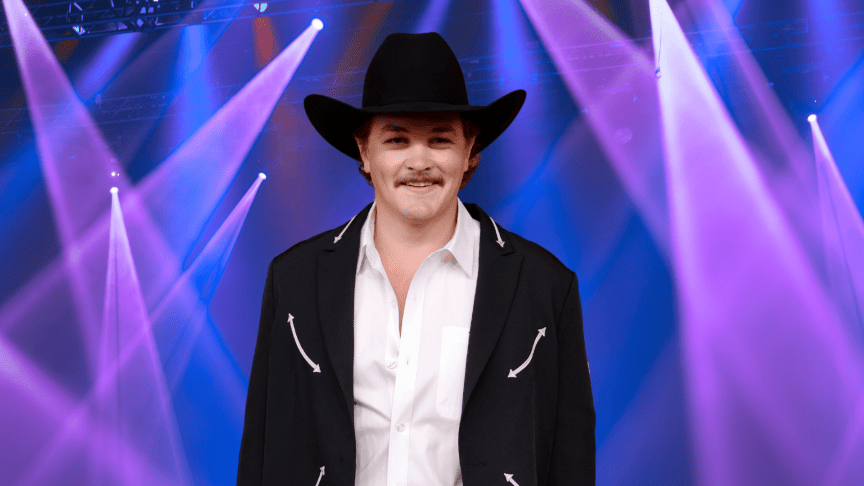 Zach Top posing in a cowboy hat in front of colorful lights.