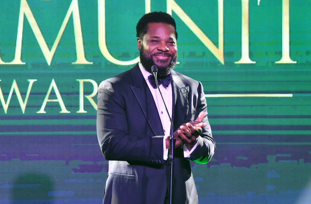 Malcom-Jamal Warner clapping in a suit.