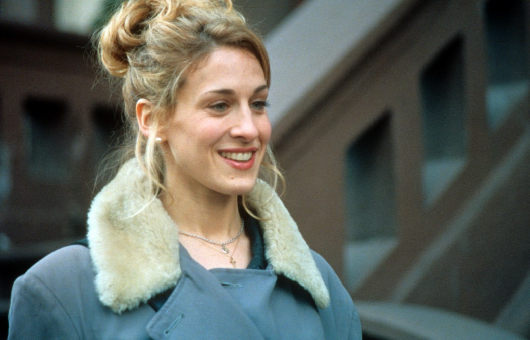Sarah Jessica Parker wearing a fur lined collar coat, with her hair pinned up and smiling in a scene from the film 'If Lucy Fell', 1996