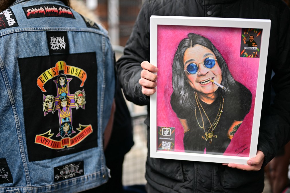 A fan holds a drawing of the late lead singer of Black Sabbath, Ozzy Osbourne