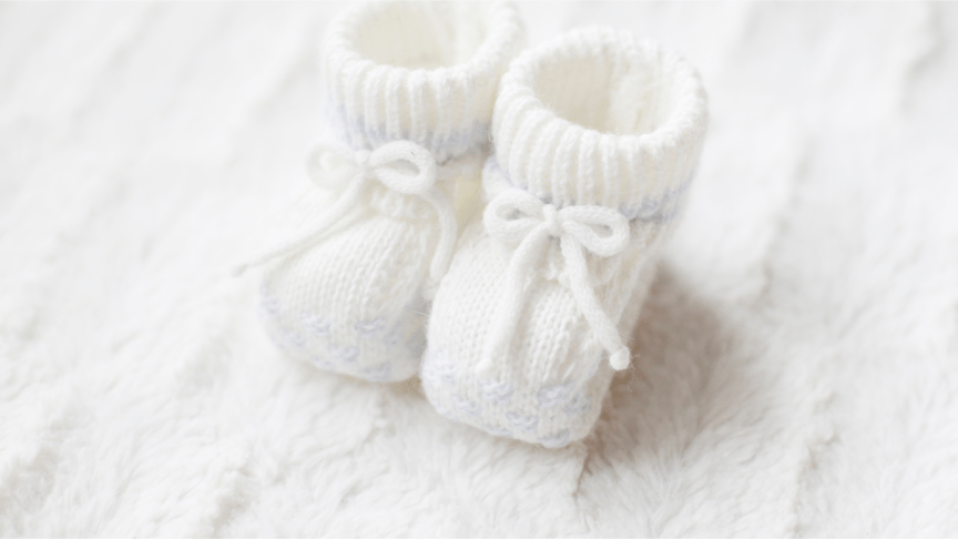 a pair of white baby booties on a white background