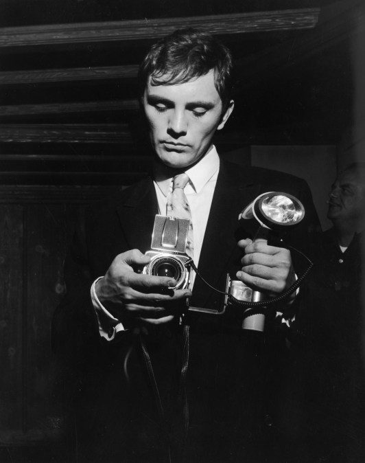 1965:  British actor Terence Stamp prepares to take a photograph