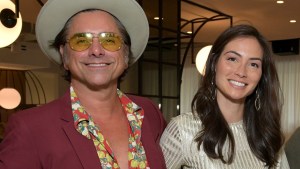 John Stamos and Caitlin McHugh smiling at an event
