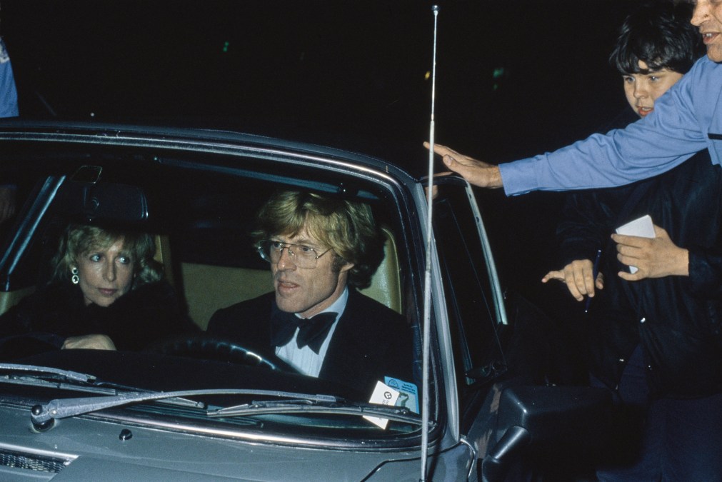 Autograph hunters beside the car being driven by American actor Robert Redford