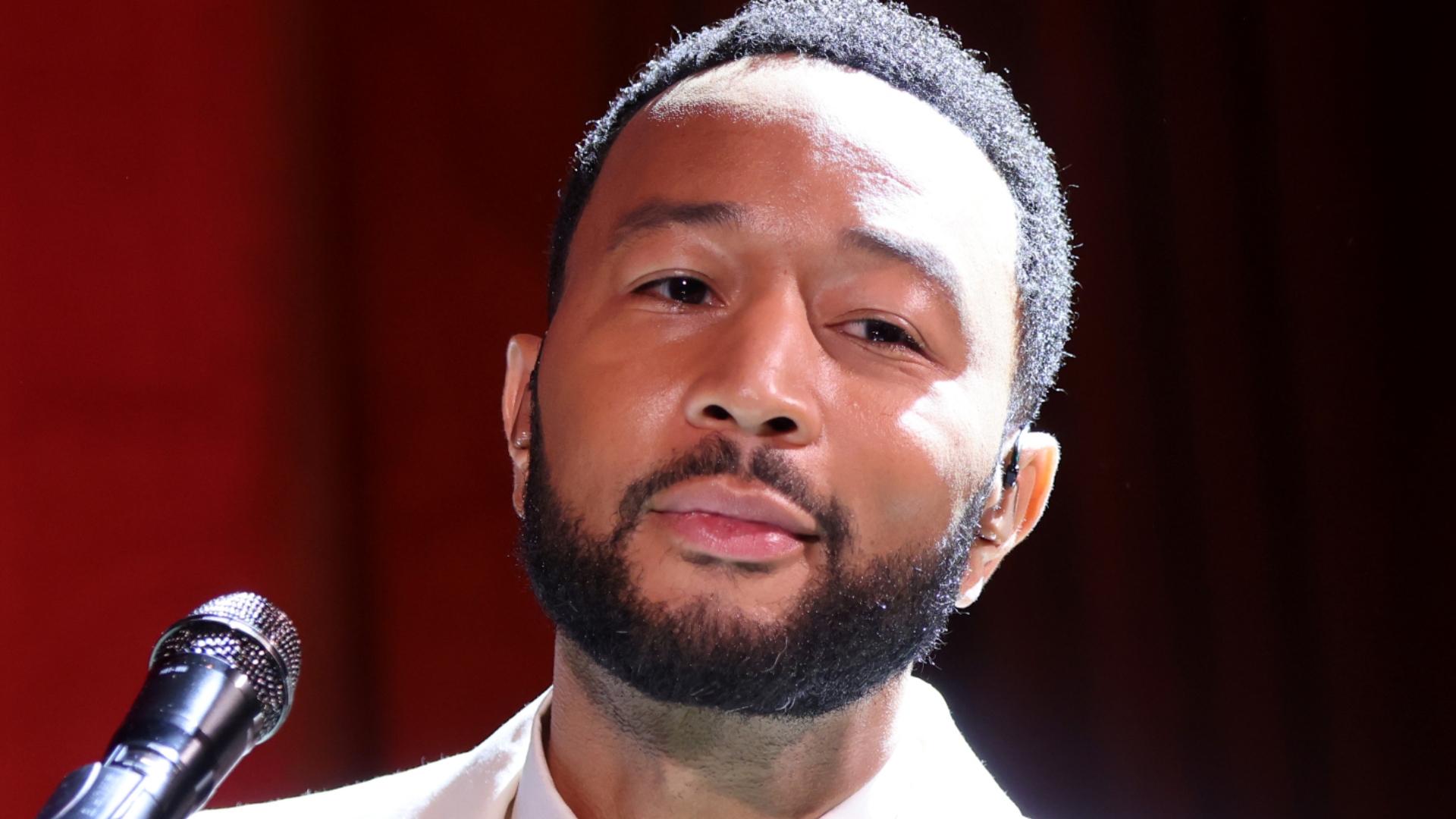 John Legend performing behind a piano at an event