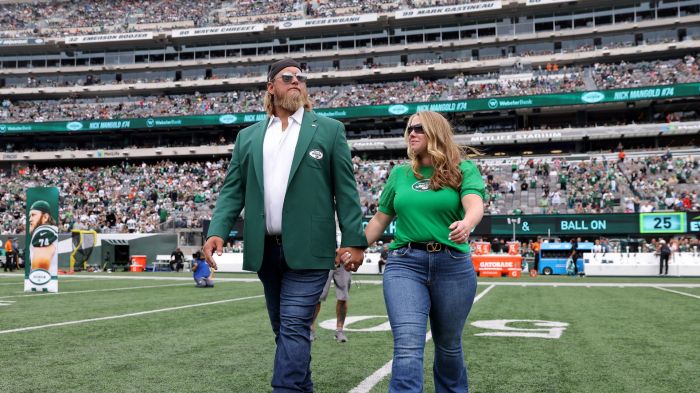 Former New York Jets player Nick Mangold walks on the field with his wife Jennifer Richmond as he is inducted into the Jets Ring of Honor during halftime of the game against the Cincinnati Bengals at MetLife Stadium on September 25, 2022