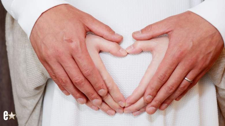 Husband and wife making a heart shape over her pregnant belly