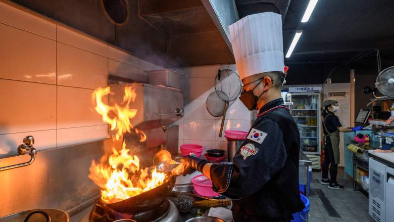 This picture taken on September 1, 2021 shows Chinese food kitchen owner and chef Park Chan-chul cooking a meal before it is delivered to a customer, at the 5Km Kitchen, a business set up in March this year to rent out kitchen spaces for food companies that only do deliveries in Seoul.