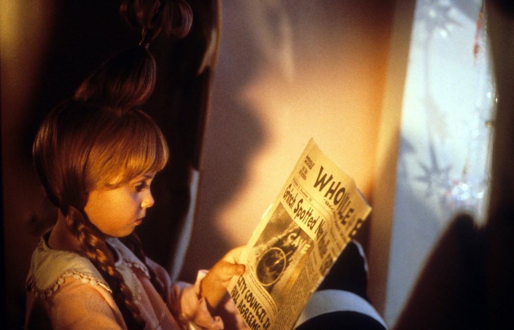 Taylor Momsen reading newspaper about the Grinch in a scene from the film 'How The Grinch Stole Christmas', 2000. 
