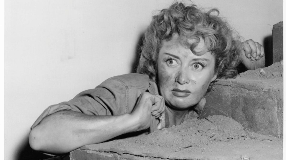 Joan Blondell cowering behind stairs in a scene from the film 'Cry 'Havoc'', 1943