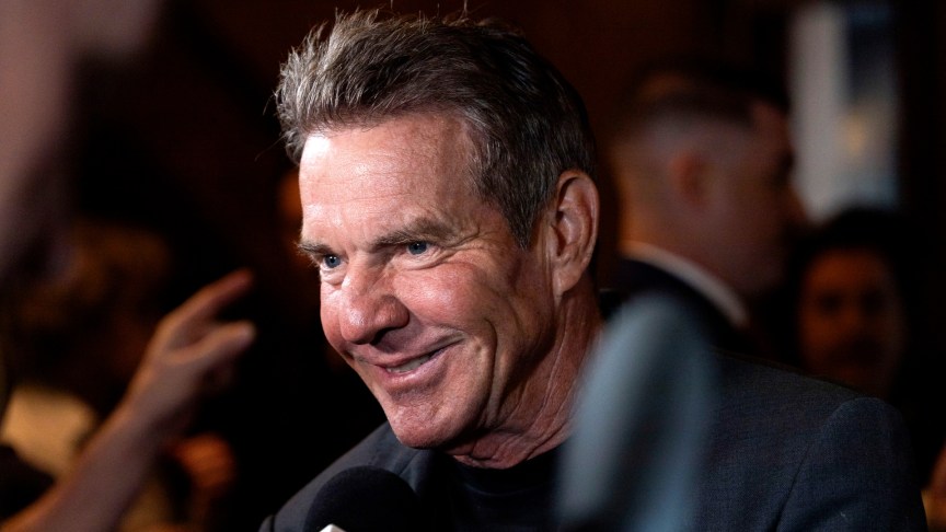 Dennis Quaid smiling while giving an interview