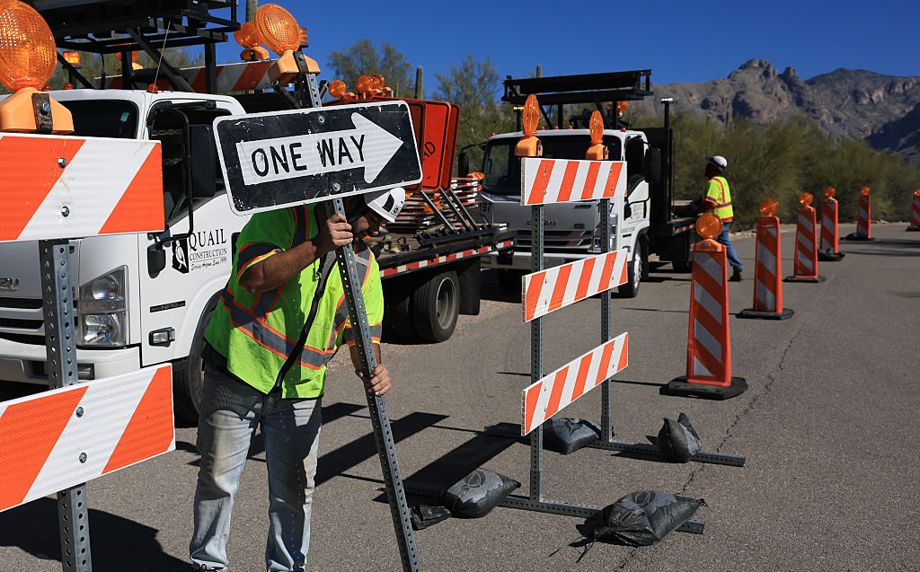 A road crew sets up signs and barricades