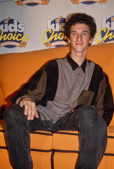 American actor and comedian Dustin Diamond, wearing a grey, black and olive green shirt, sitting on an orange sofa in the 6th Annual Nickelodeon Kids' Choice Awards press room, at Universal Studios Hollywood in Universal City, California, 14th November 1992.