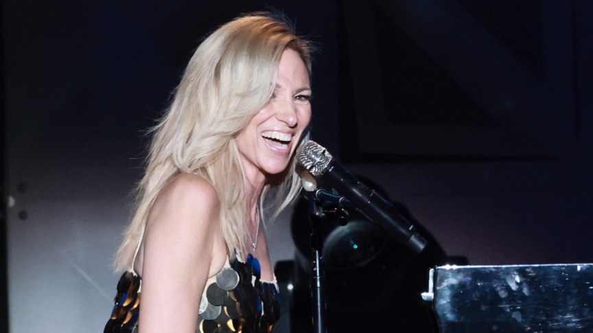 Debbie Gibson onstage with a microphone and piano