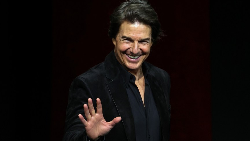 Tom Cruise smiling and waving at an event