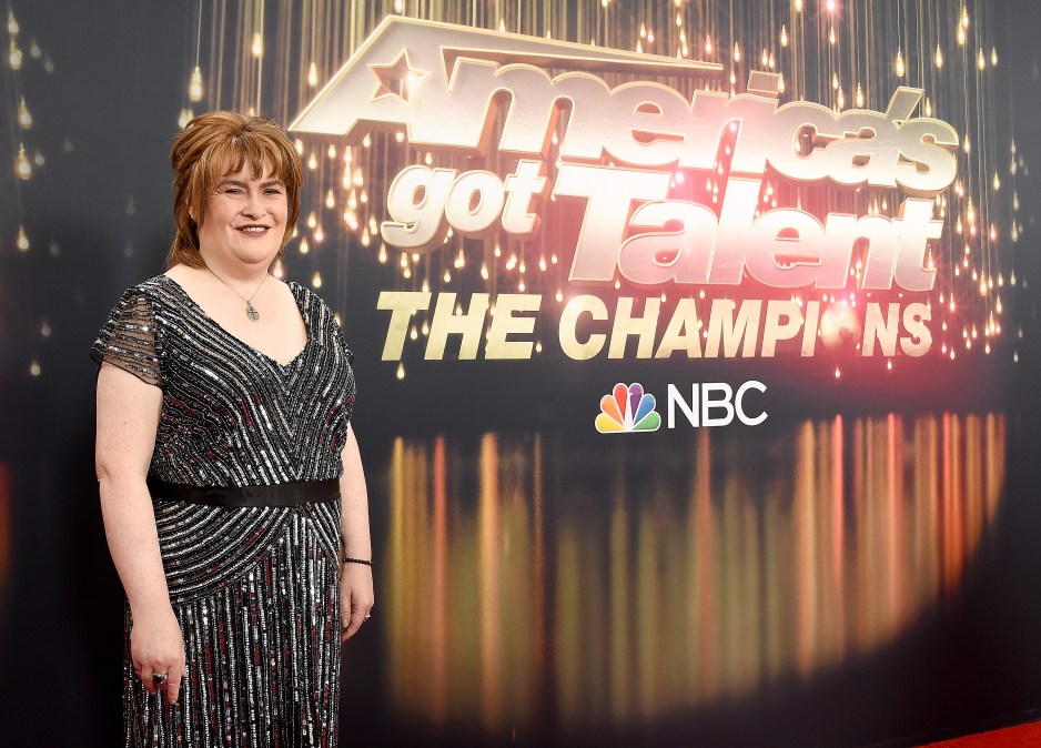 Susan Boyle poses infront of a "America's Got Talent: The Champions" poster