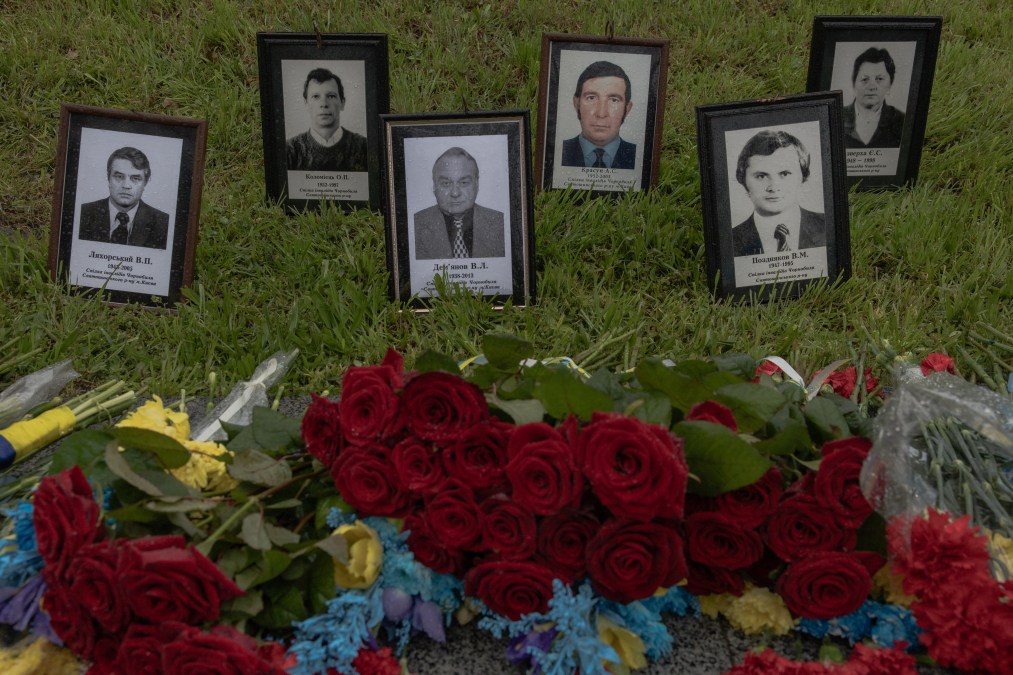 This photograph shows portraits displayed next to flowers at a memorial for the victims of Chernobyl, on the 40th anniversary 