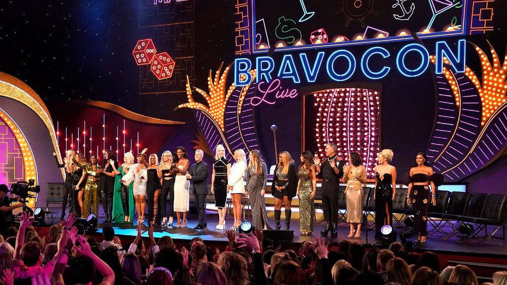 Bravo personalities gather on stage during a live BravoCon event as fans cheer from the audience.