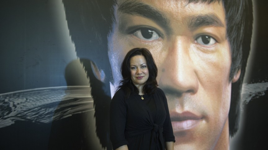 Shannon Lee stands infront of photo of Bruce Lee