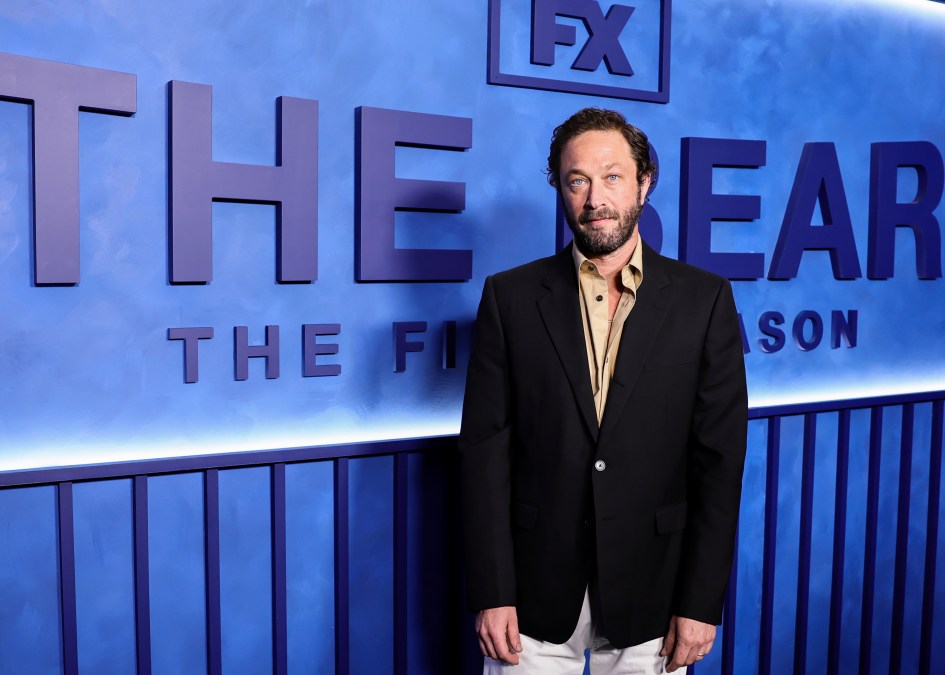 Ebon Moss-Bachrach wearing a tailored blazer portrait shot against the blue FX backdrop at the press event.