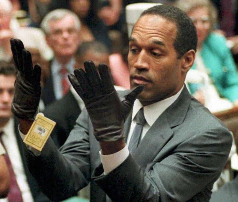 This 21 June 1995 file photo shows former US football player and actor O.J. Simpson looking at a new pair of Aris extra-large gloves that prosecutors had him put on during his double-murder trial in Los Angeles