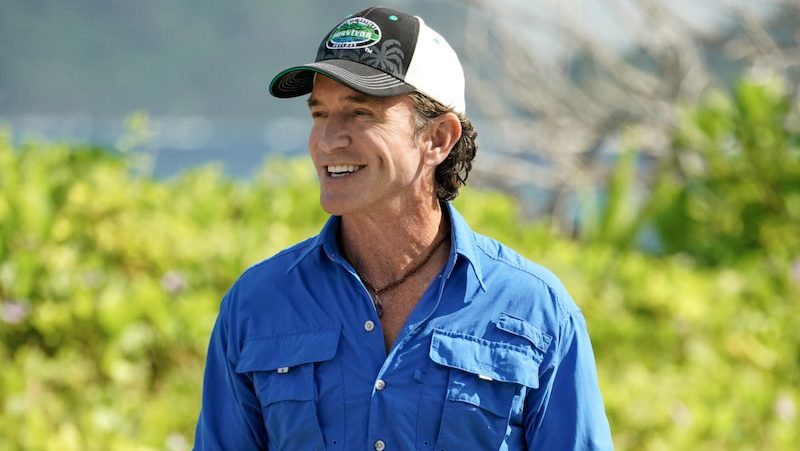 Jeff Probst smiles while wearing a "Survivor" hat during filming as a new official companion book celebrating all 50 seasons is announced.