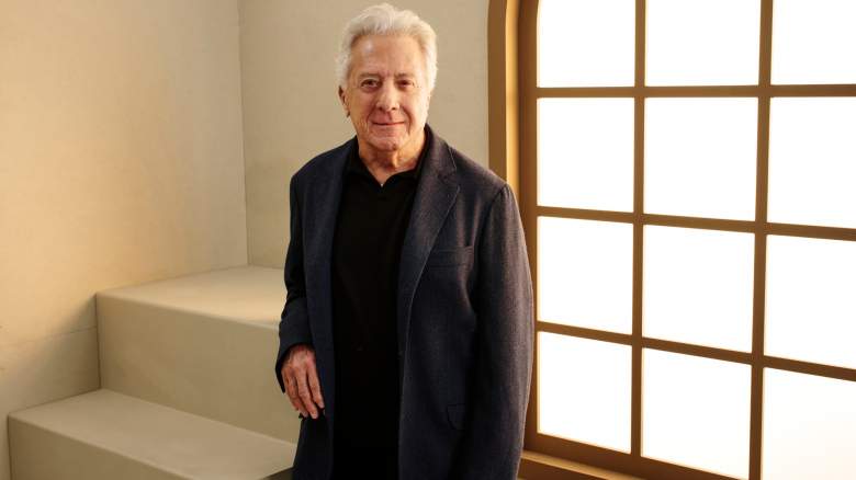 Dustin Hoffman poses in a black shirt and suit.