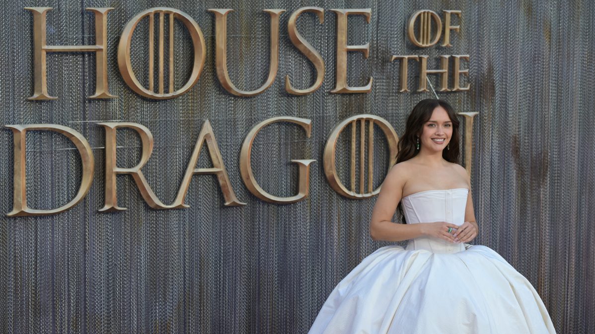 Olivia Cook standing in front of the House of the Dragon logo while at the world premiere of Season 3