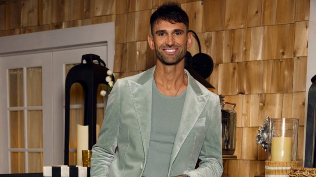 Carl Radke stands in a green shirt and blazer on the 'Summer House' reunion set.