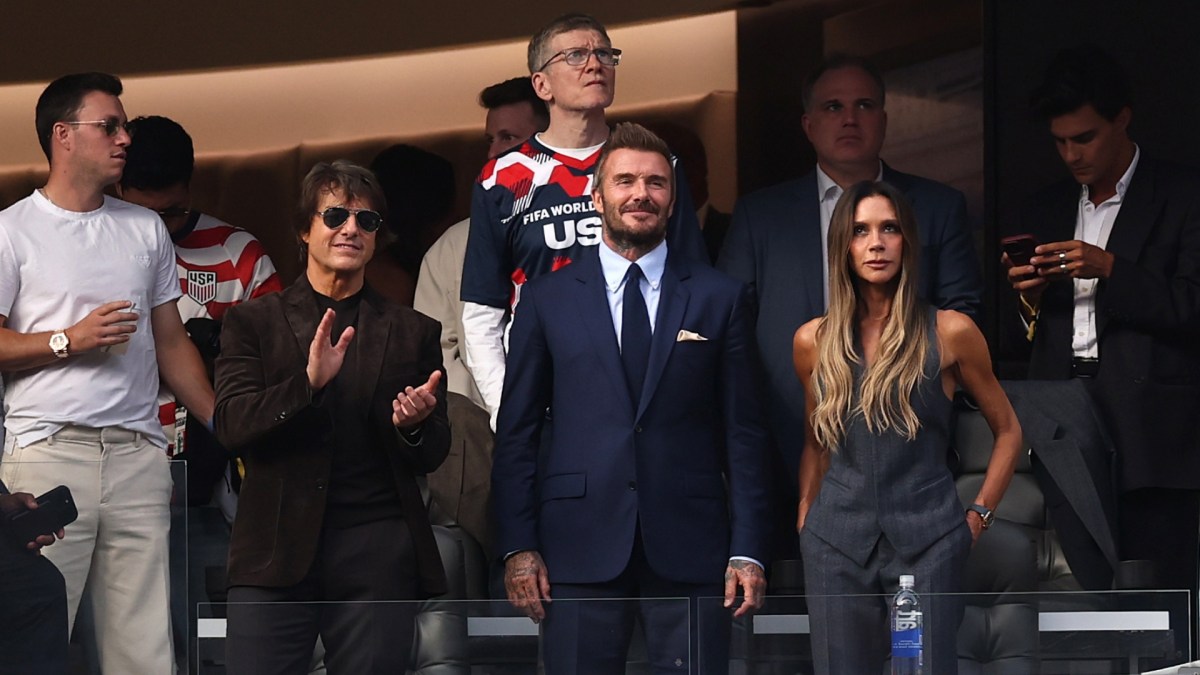 Tom Cruise, David and Victoria Beckham stand at their seats in the World Cup stadium.