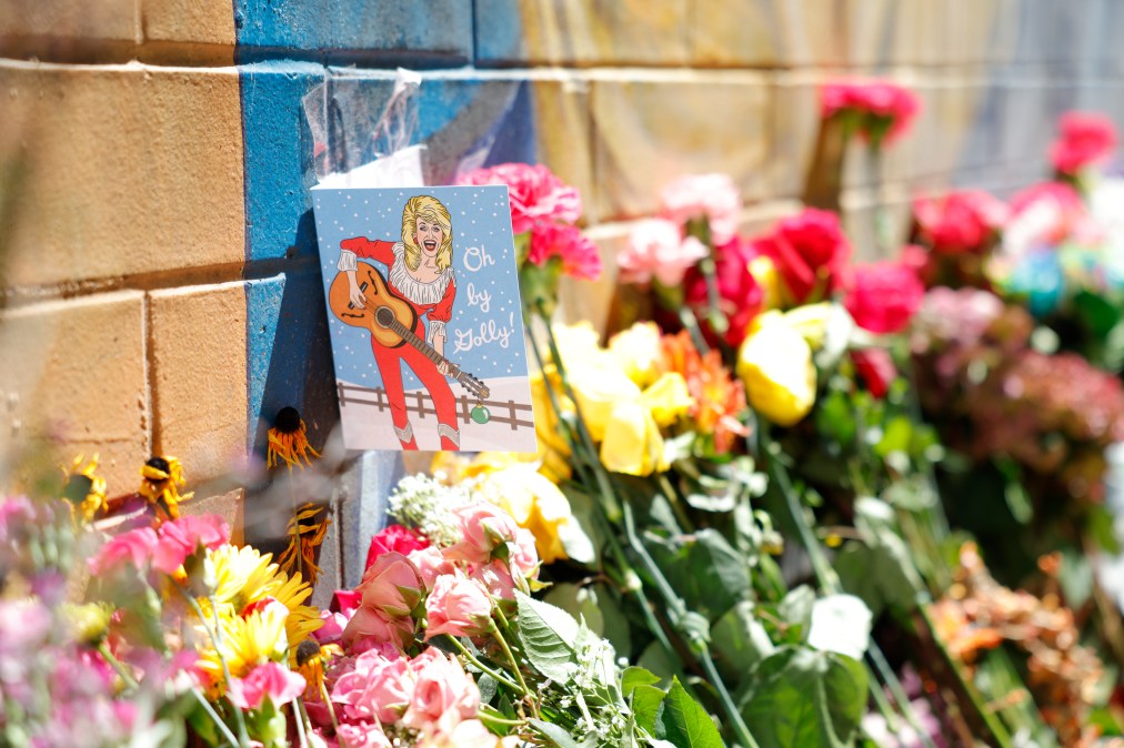 Flowers and letters are placed at the Dolly Parton mural