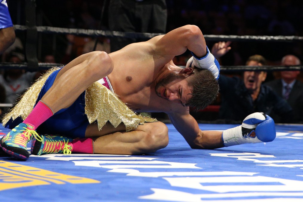A photo of Prichard Col&oacute;n on the floor holding the back of his head with a painful expression on his face.