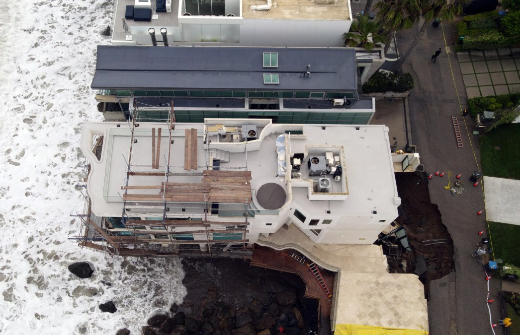 This aerial view shows a sinkhole on a street and driveway of a seaside home